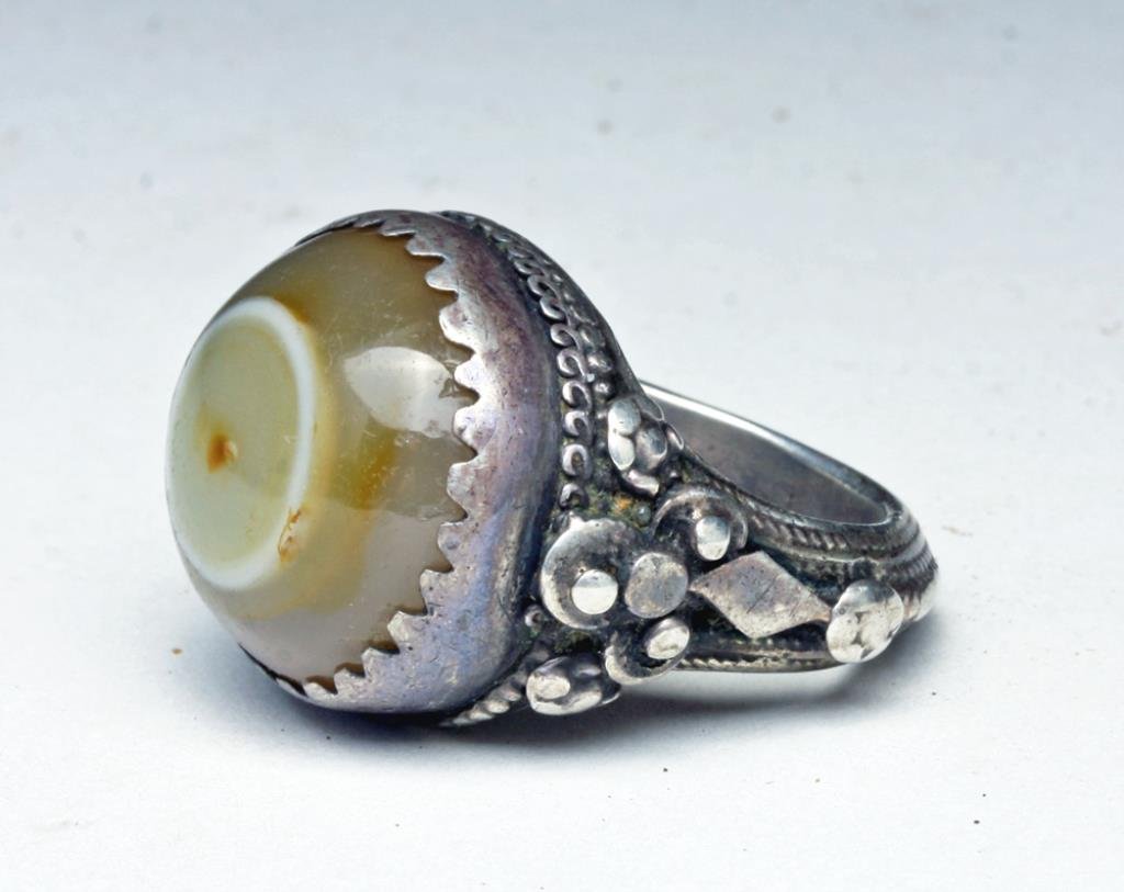 Antique Turkomen Silver and Agate Ring: Afghanistan/Pakistan, Ca late 19th century. Attractive silver ring with floral designs to each side, holding large "eye" cabochon agate. 20mm inside dimension, about US size 8. 31mm high.
