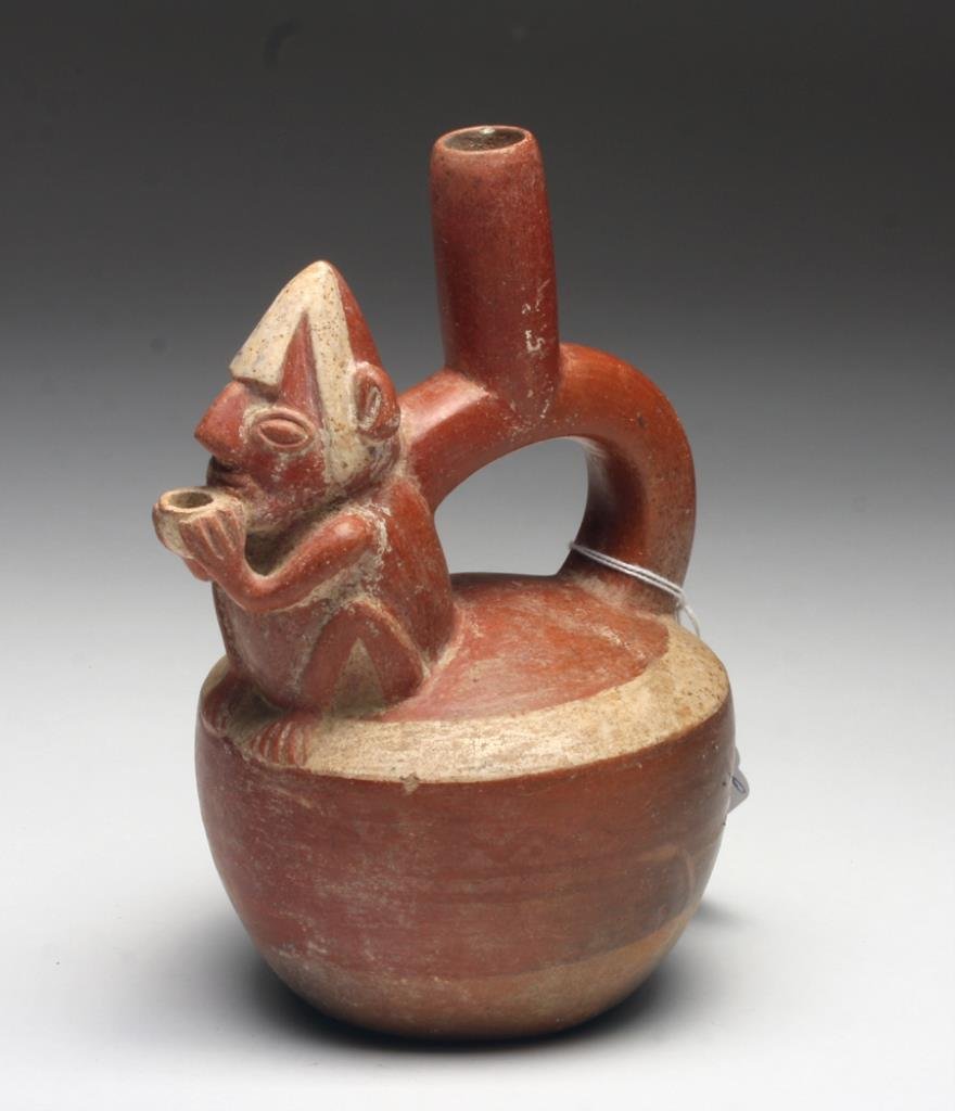 Inca Bi-Chrome Pottery Stirrup Jar: Pre-Columbian, Central Peru, Ca 1400 to 1500 CE. Lovely and choice pottery stirrup jar depicting a seated male, drinking from a small kero, painted hat upon his head. A classic Inca example! 7-1/2" H.