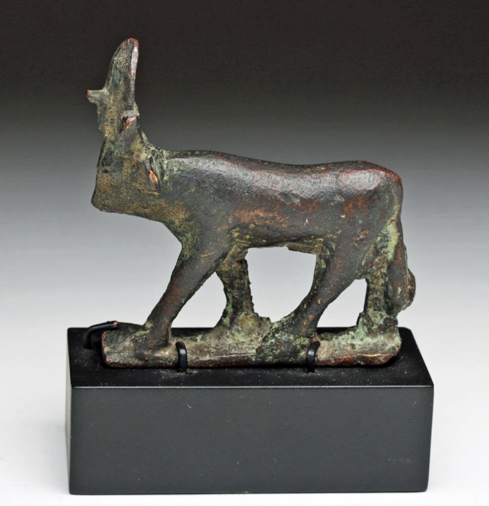 Egyptian Bronze Apis Bull, Ex-Sothebys: Egypt, Late Dynastic Period, Ca 662 to 330 BCE. Cast bronze Apis bull on integral plinth, shown wearing solar disc and uraeus. 2-7/8" L by 2-3/4" H, not including custom base. Provenance: Ex-A. Carraf