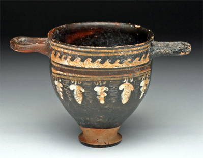 Greek Apulian Gnathian Skyphos - Vine Pattern: Apulia, near the town of Ignazia, Ca 340 to 325 BCE. Fine and wonderfully thin pottery wine cup (skyphos) with short foot, thin base and twin horizontal handles. Decoration consists of grape vines