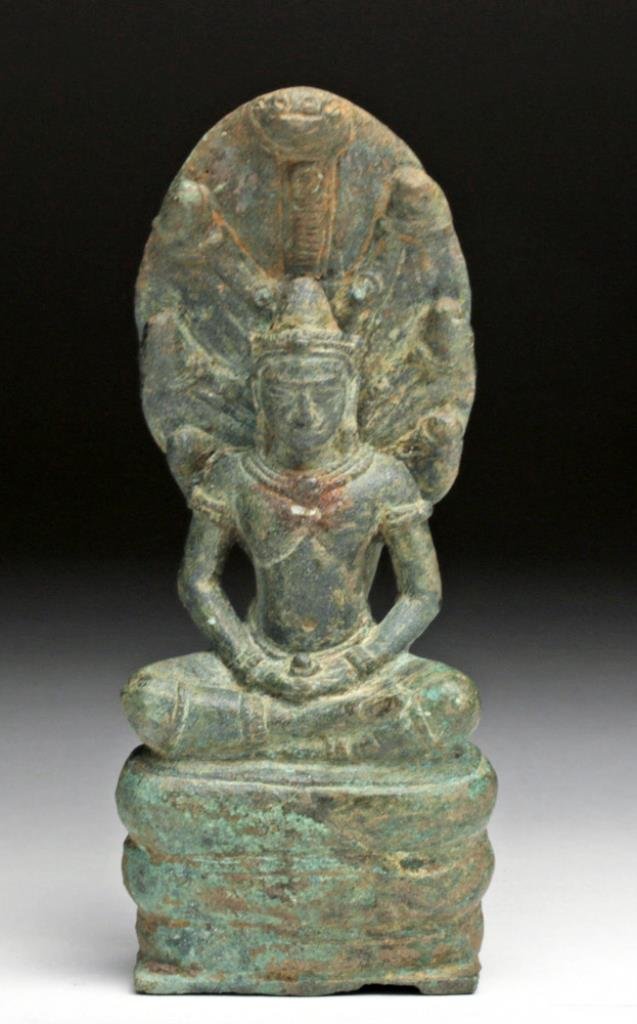 Khmer Bronze Figure of Buddha Muchalinda: Cambodia, Khmer/ Lopburi, 13th century. Well cast and sensitively modeled with Buddha seated in meditation on the coils of Muchalinda, rising to form a seven-headed hood sheltering Buddha, his face wi