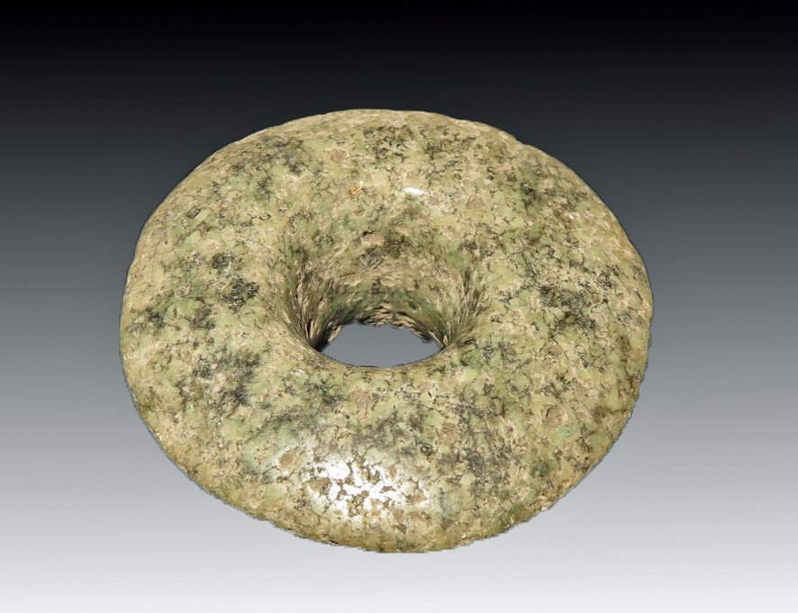 Pre-Columbian Greenstone Ear Flare: W. Mexico, Ca 300 BCE to 300 CE. A nice carved green stone ear flare. Mottled stone with flat upper section and spooled reverse. 2-3/4" W. Provenance: Ex-Lynn Langdon collection acquired in the 1950's