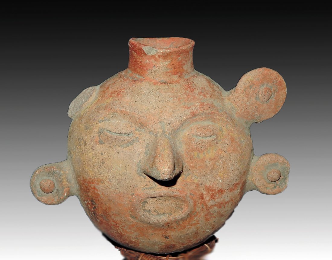 Pre-Columbian Colima Sun / Face Jar: Colima, W. Mexico, Ca 300 BCE to 300 CE. Another rare vessel! Rounded jar in the form of a human or solar face. 4 rounded discs appear around the face (one now missing). 7 1/4" wide Provenance: Ex-Lyn