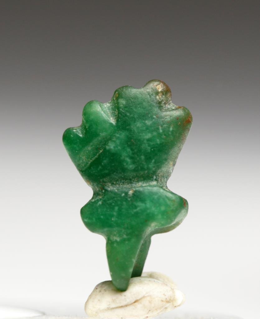 Rare Moche Emerald Amulet: Pre-Columbian, Peru, north coast, Ca 200 to 400 CE. Amulet carved from Colombian emerald - certainly traded up and down the Pacific Coast. Bright green stone carved in the form of a thumb resting betw