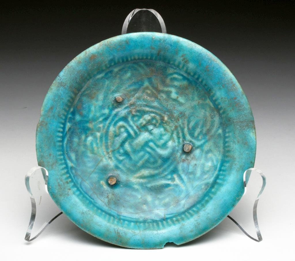 Islamic Blue Glazed Dish, Kashan: Iran, Ca 12th to 14th century, possibly Kashan region. Stunning sky blue ceramic plate impressed in the center with floral patterns. Areas of silvery iridescence! 6-1/8" D. Provenance: Ex Private Smit