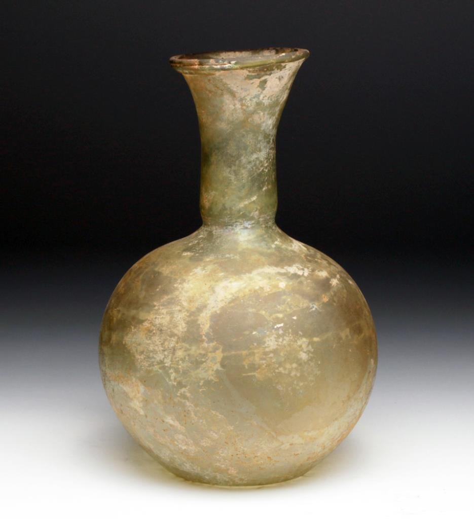 Another Tall Roman Glass Long-Necked Bottle: Roman, acquired in Beirut, Lebanon, Ca 200 to 300 CE. Large and thin glass bottle in light green glass, with very long neck, slightly flared rolled rim, no pontil on underside. 9-1/4" H. Provenance: E