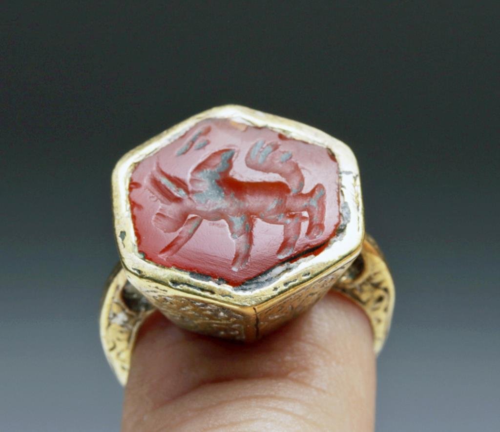 6-Sided Bactrian Carnelian Intaglio, Set in Ring: Afghanistan, Ca late 2nd to early 1st millennium BCE. Unusual 6-sided carnelian intaglio with a large-humped bull. Intaglio set in modern gold-tone ring and is ready to wear! Intaglio measures 5/8" ac