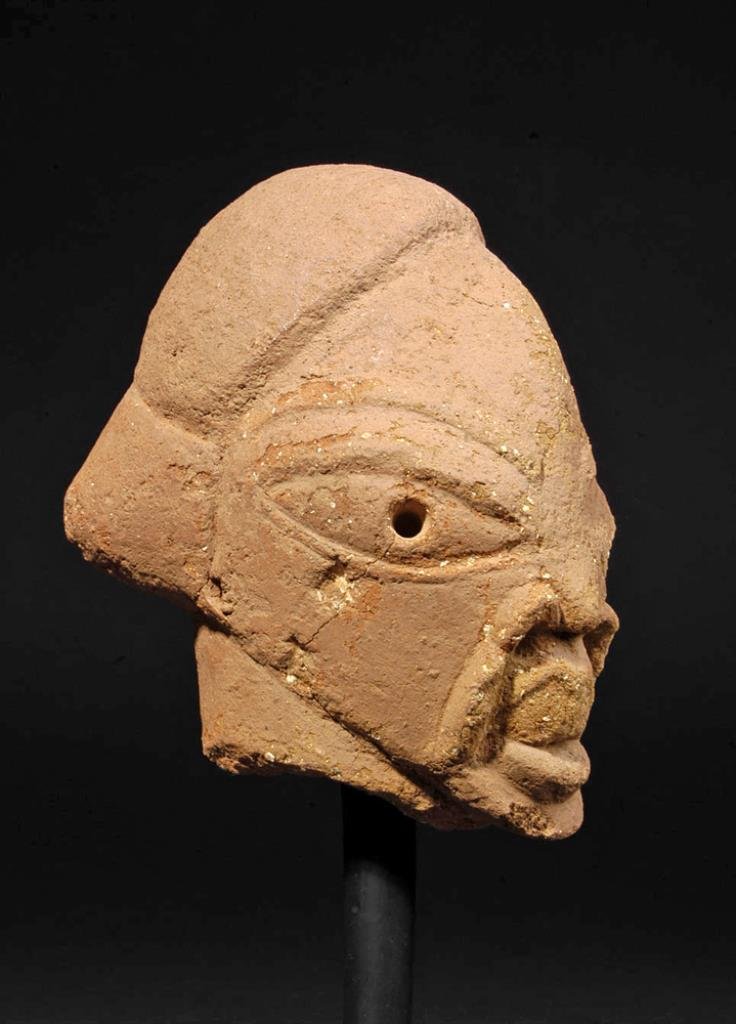 Nok Culture Terracotta Head Fragment: Jos Plateau region, Central Nigeria, West Africa, 500 BCE to 200 CE. Terracotta with heavy temper and remains of a finer burnished surface slip. 6-1/2" H. Mounted on steel base. Classical Nok terracot