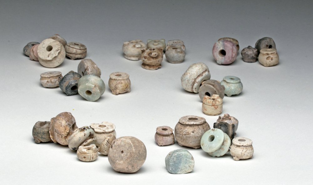 50 Pre-Columbian Stone / Clay Pot Whorls and Beads: Western Mexico, 300 BCE to 1300 CE. A large collection of 50 pieces offering a variety of shapes, sizes and colors of mainly whorls with a few beads, ranging in size from 1/2" to 1". Much to select fr