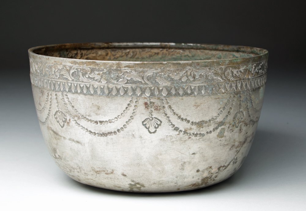 Early Cambodian Khmer Silver Bowl: Cambodia, Late Khmer to Oudong Era, Ca 1300 to 1700 CE. Large silver bowl with nearly straight walls and rolled rim. Exterior decorated with floral decoration just below rim, with repeating elongated 