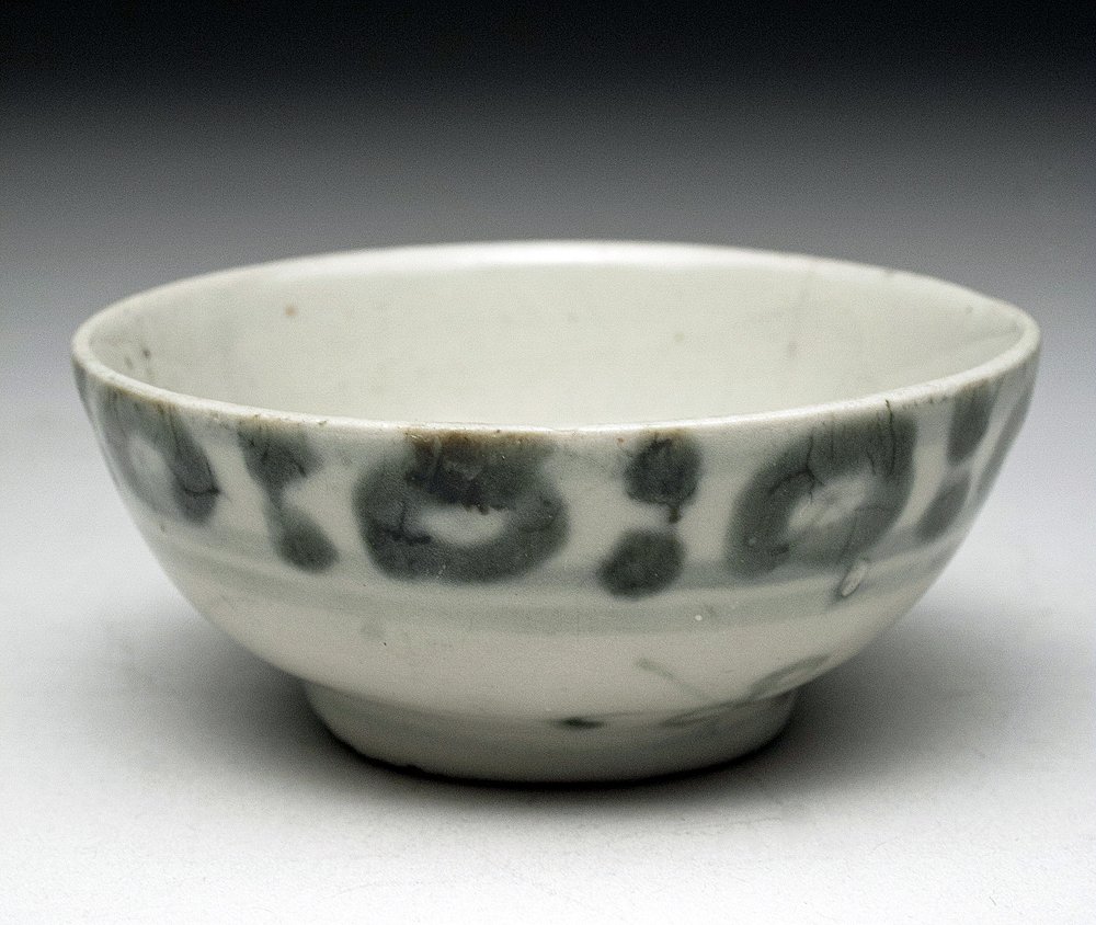 Chinese Ming Dynasty Swatow Bowl: China, Ming Dynasty, ca. 1300 - 1600 CE. Utilitarian porcelain cup sits atop small foot, with faded blue/black floral design. The name "Swatow" most probably derives from Shantou in China, an old junk