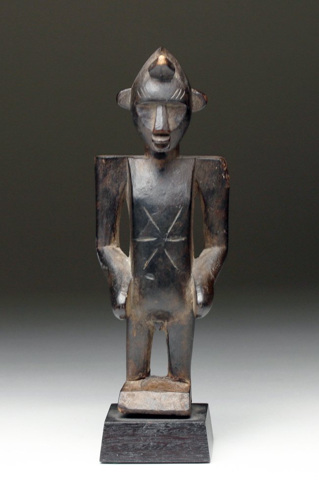 Senufo Wood Carved Tugu Bele Figure: Ivory Coast, 19th to early 20th Century CE. Blackish shiny patina, wonderful form, flat shoulders, high arched head. Star shape incision at stomach. Size: 7"H (17 cm) + custom mount. Nice dark patina.
