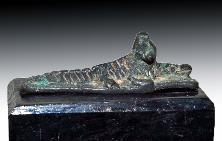 Egyptian Bronze Sobek Figure: Egypt, Late Period, ca. 600 - 30 BCE. Rare depiction of Sobek depicted as a crocodile with remains of his typical plumed crown. Sobek was the ancient god of crocodiles. He was a god of the Nile who br