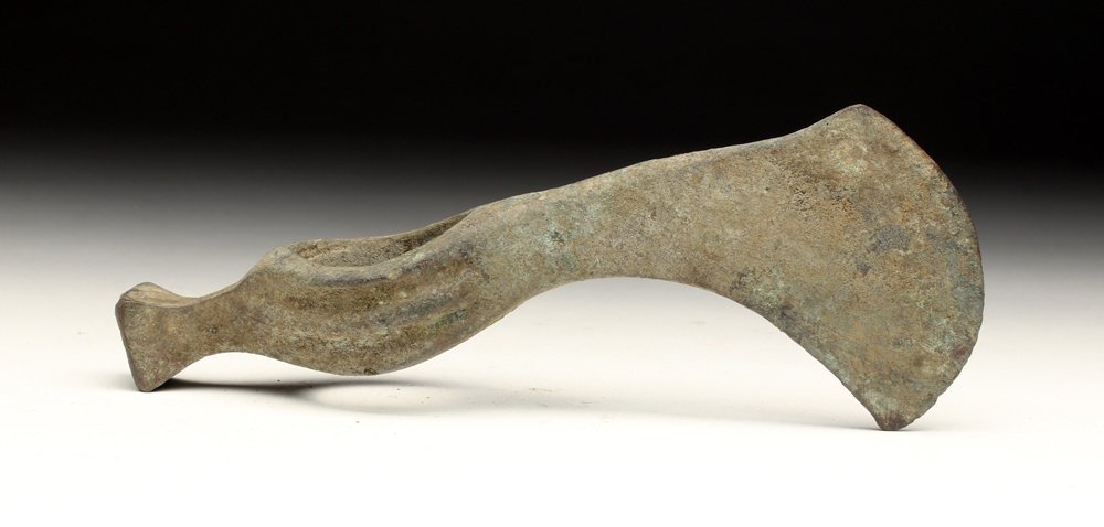Hallstatt Bronze Axe Head with Curved Blade: Eastern Europe, ca. late 2nd - early 1st millennium BCE. Ah, the tools of the ancients! This Hallstatt bronze axe head was cast with a downward curving blade with ribs on the shaft and a butt that res