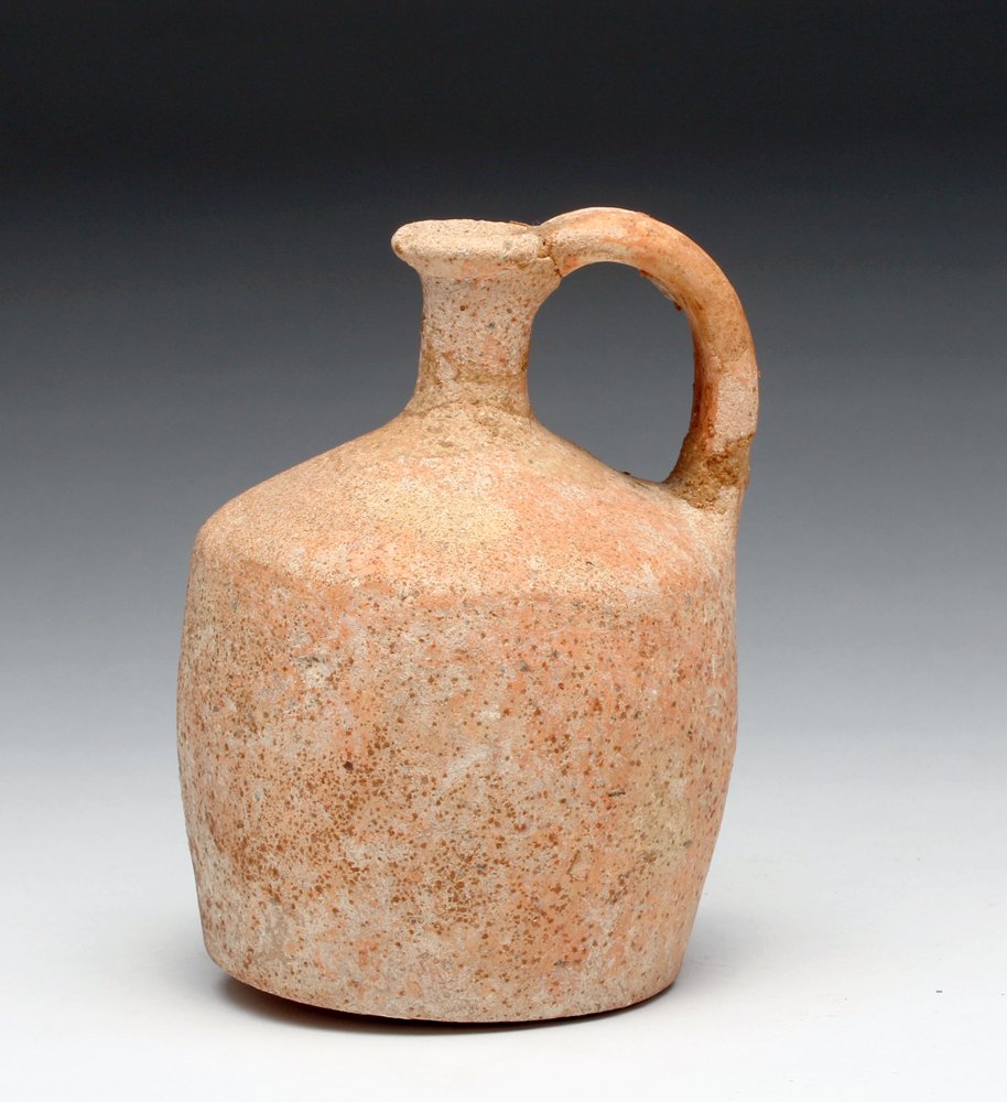 Roman Redware Pottery Jug: From the Eastern Roman Empire, ca 2nd to 3rd century CE. Pottery pouring vessel in near cylindrical form, with short straight neck, flaring rim and twin strap handle. Size: 5-1/4" H. Provenance: Ex-W