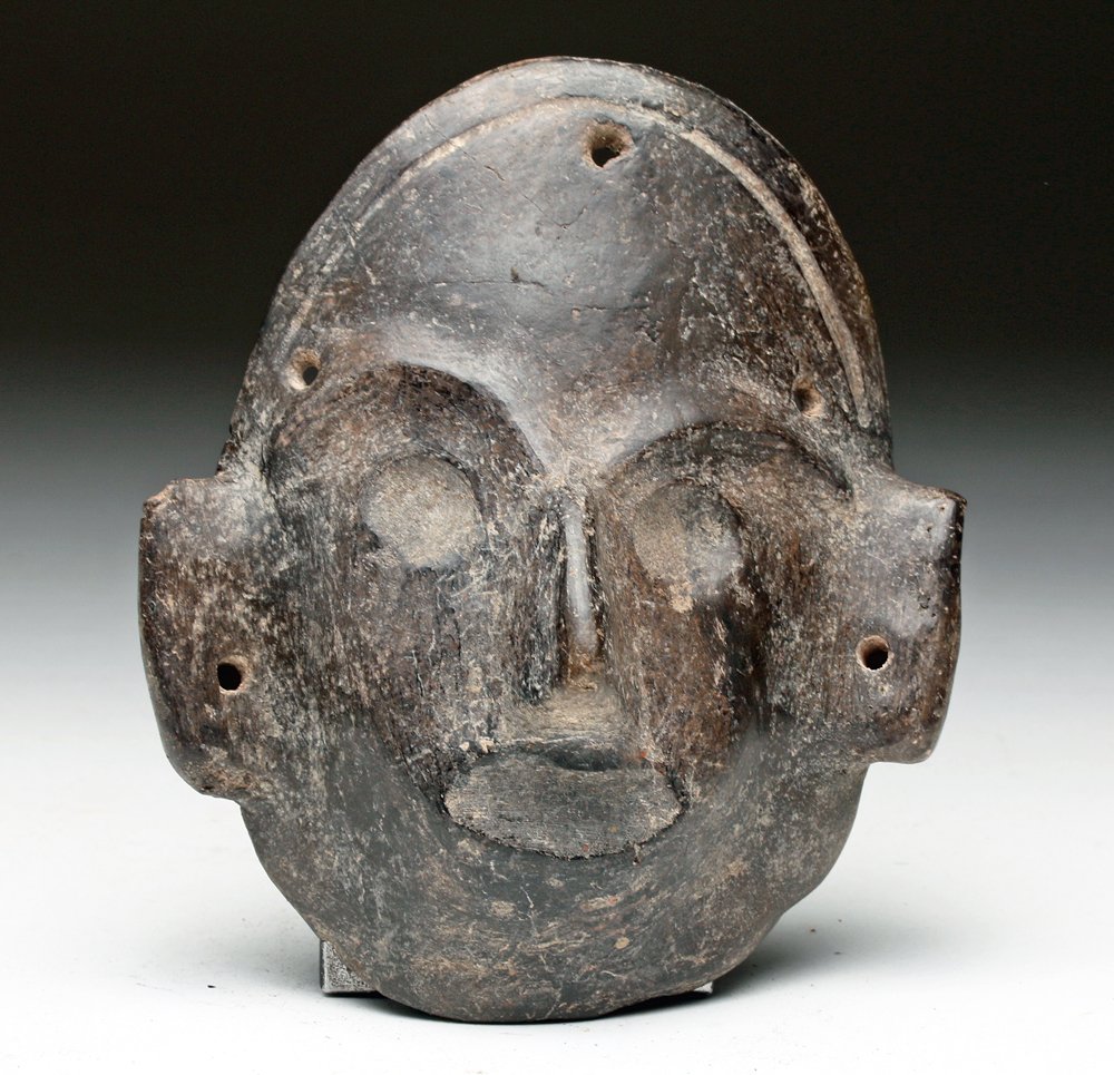 Colima Terracotta Maskette: Pre-Columbian, West Mexico, Colima, ca. 200 BCE to 200 CE. A refined ceramic maskette in a monochrome black finish with charmingly minimalist facial features - think Modigliani - and angular ear forma