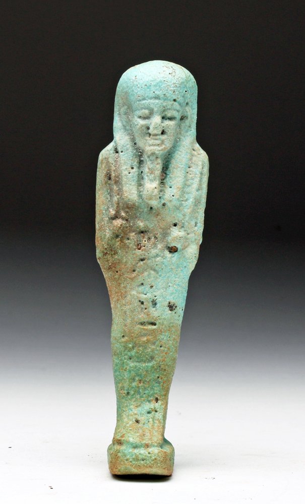 Egyptian Green Faience Ushabti: Egypt, Late Dynastic, 26th to 30th Dynasties, ca. 662 to 315 BCE. Standing mummiform figure ready to do his master's bidding in the afterlife. Holds crook and flail, with band of hieroglyphic text dow