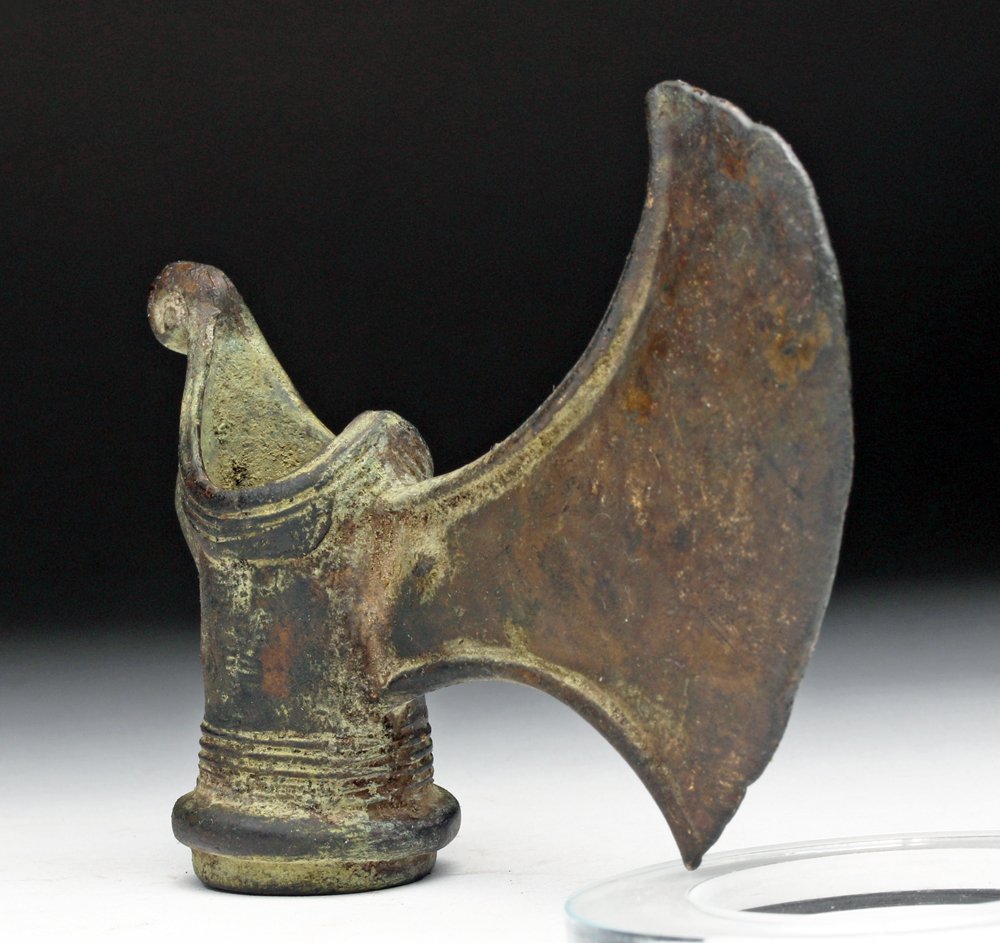 Elamite Bronze Axe Head: Middle East, Southwest Iran, Old Elamite, early 2nd millennium BCE. An ancient bronze axe head with a crescentic blade, with ribbing around the edges of the shaft, the top end resolving in a tight spi