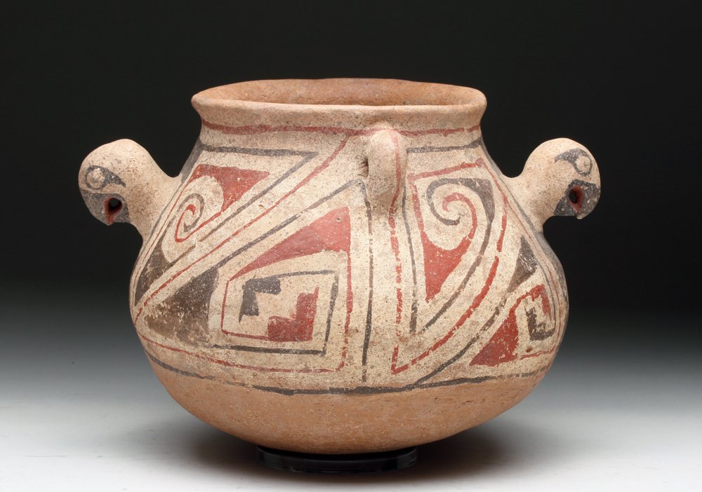 Unusual Casas Grande Ramos Polychrome Olla: Pre-Columbian, Northern Mexico, ca. 1100 to 1200 CE. Unusual pottery jar decorated in added red, white and black slip over buff base. To each side of the olla are parrot heads in full relief. Each wit