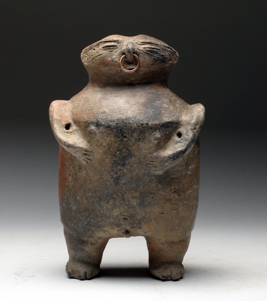 Quimbaya Pottery Standing Figure w/ Gold Nose Ring: Pre-Columbian, Colombia, Cauca River Valley, ca. 13th to 16th century CE. Rare hollow molded pottery standing male, shown nude with hands to his belly, stippled surface to each side of eye coffee-bean