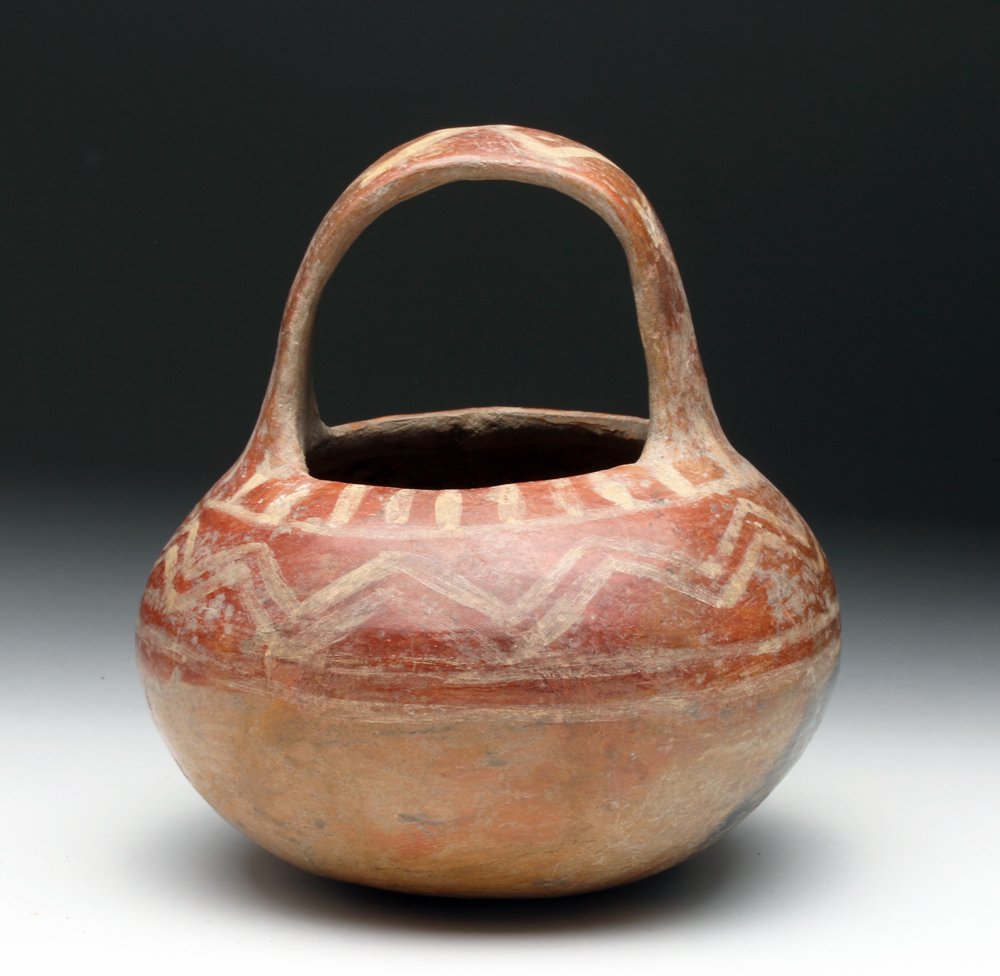 Rare Zacatecas Pottery Handled Jar: Pre-Columbian, Mexico, Zacatecas, ca. 400 BCE to 200 CE. Attractive and unusual pottery jar. Bulbous base with looping strap handle, decorated in red slip and ocher zigzags and stripes. Size: 6-1/4"H 