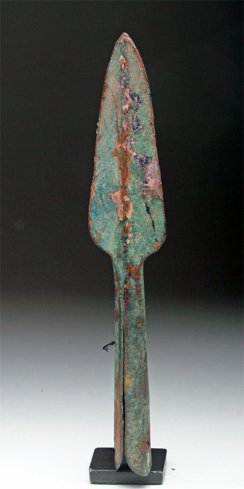 Published Persian Bronze Spearhead: Iran, Achaemenid period, ca. 539-331 BCE. Published cast bronze spear tip with long blade and pronounced blood ridge. The conical socket is long and folded and features a rivet hole in either side. An