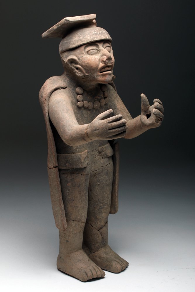 Vera Cruz Terracotta Figure in Ceremonial Regalia: Pre-Columbian, Mexico, Vera Cruz/Veracruz, ca. 400 to 600 CE. An expressive and quite tall Vera Cruz terracotta figure, dressed in ceremonial regalia comprised of a long cape, fanciful headdress, wide