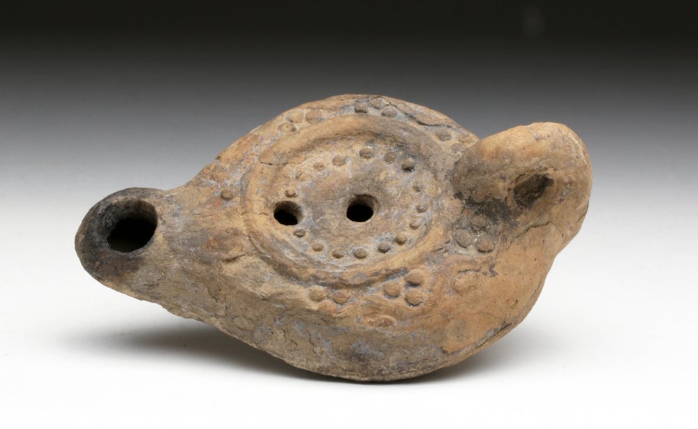 Ancient Terracotta Roman Oil Lamp - Grapevines: Rome, ca. 2nd century CE. Hand-molded terracotta oil lamp covered with depictions of grapes and grape vines. Perfect example for any wine lover's collection! Lamps such as this were filled with olive 