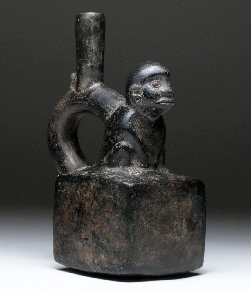 Chimu Blackware Stirrup Vessel with Monkey: Pre-Columbian, North Coast Peru, Chimu, ca. 1000 to 1400 CE. A handsome blackware mold-made stirrup vessel with a large monkey perched upon a cube-shaped base and a smaller monkey crawling up the hand