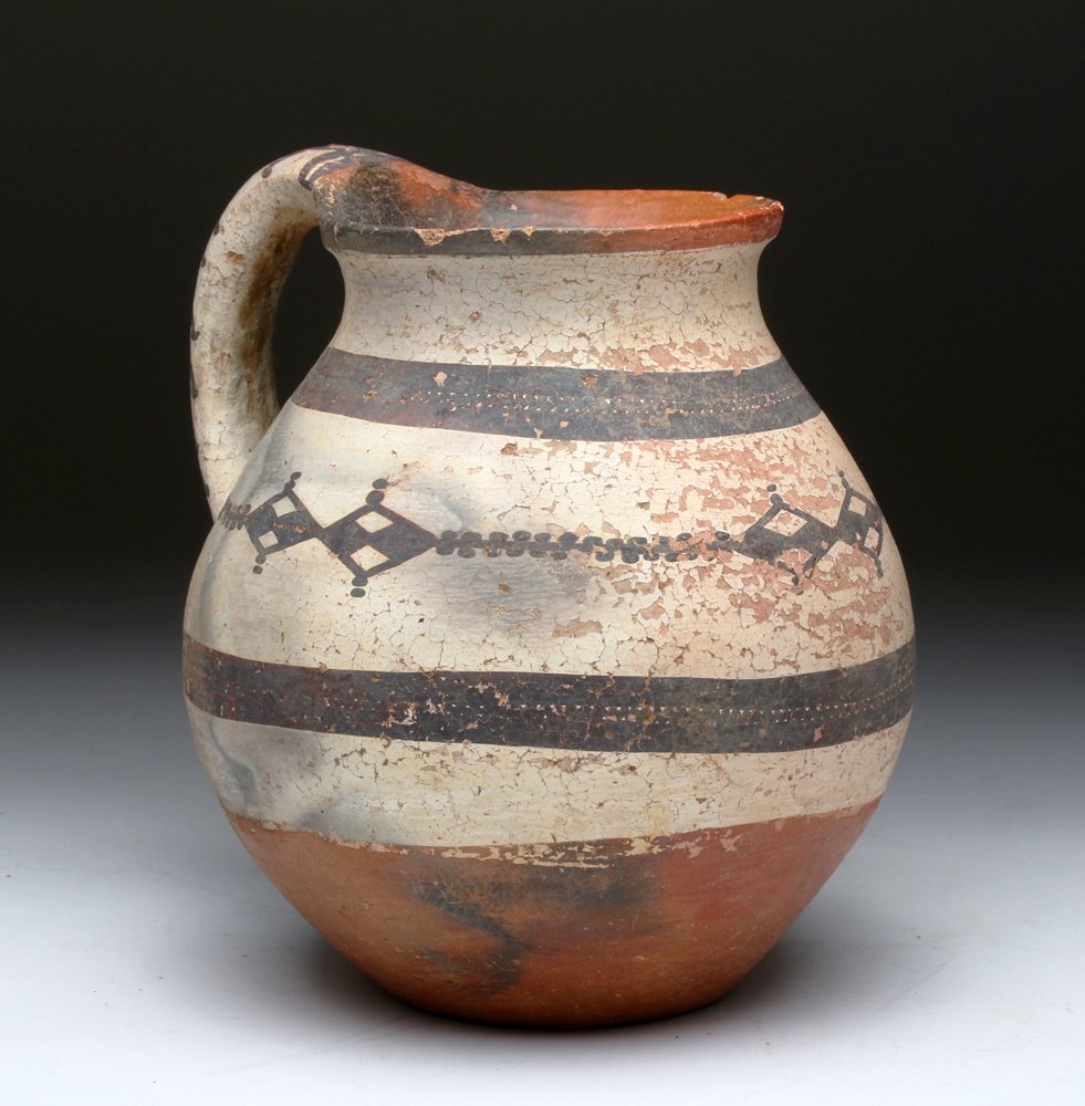 Islamic White-Slipped Pottery Jug: Central Asia, Iran / Iraq, ca. 800 to 1100 CE. A fine pottery olpe or jug of medium-sized globular body with a substantive loop handle. Approximately 2/3 of the vessel is covered in white slip with at