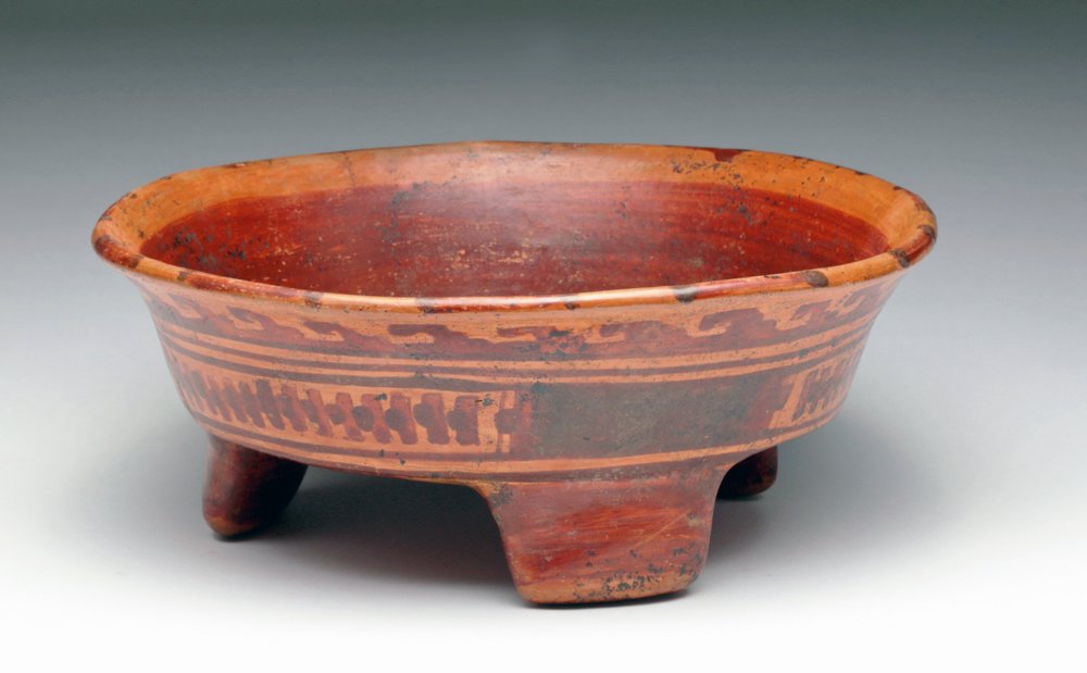 Mayan Ulua Valley Polychrome Tripod Bowl: Pre-Columbian, Mayan territories, ca. 550 to 900 CE. Vibrant and attractive polychrome pottery tripod, in shades of red and orange with wave pattern just below outer rim and three panels of nets wit