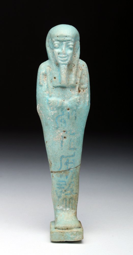 Egyptian Faience Ushabti - Glyph Band Down Front: Egypt, Late Period, ca. 664 to 332 BCE. Shabti in traditional mummiform pose wearing tripartite wig and false beard, arms folded across chest holding crook and flail, hieroglyphic text down front. Pil