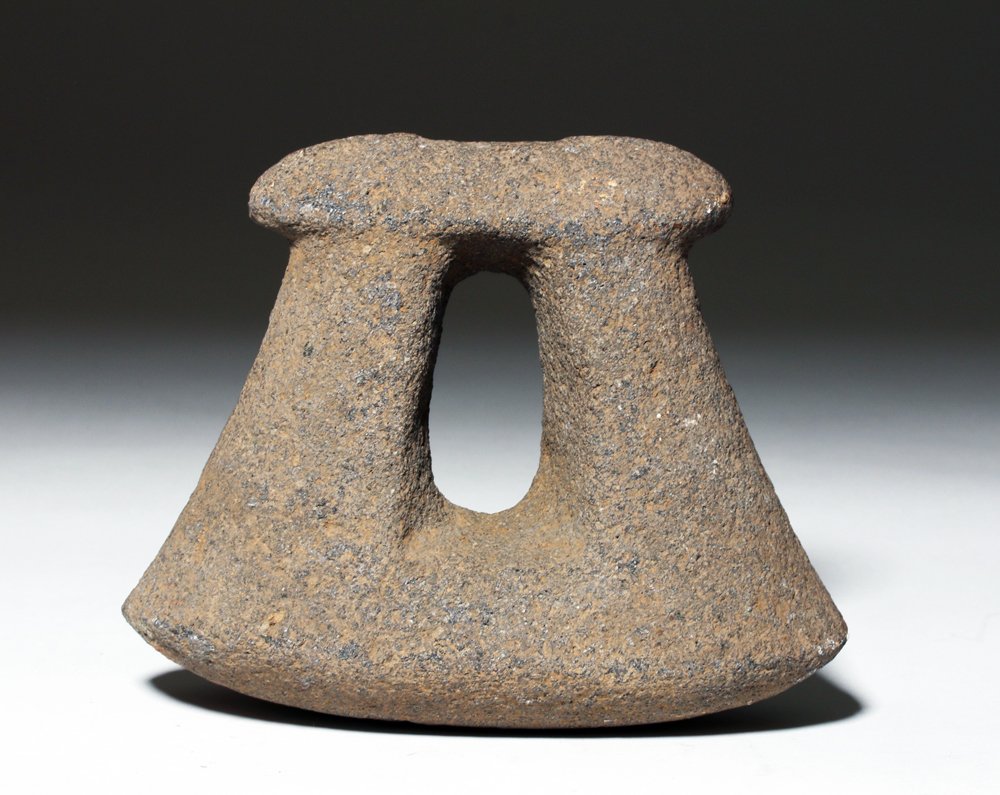 Guerrero Stone Stirrup Pestle: Pre-Columbian, Mexico, Guerrero, ca. 500 to 300 BCE. An unusual, stirrup shaped stone pestle of a substantive size, comprised of grey stone with reddish hue. Size: 6-3/4" x 5-1/4" (17.1 x 13.3 cm). Pr