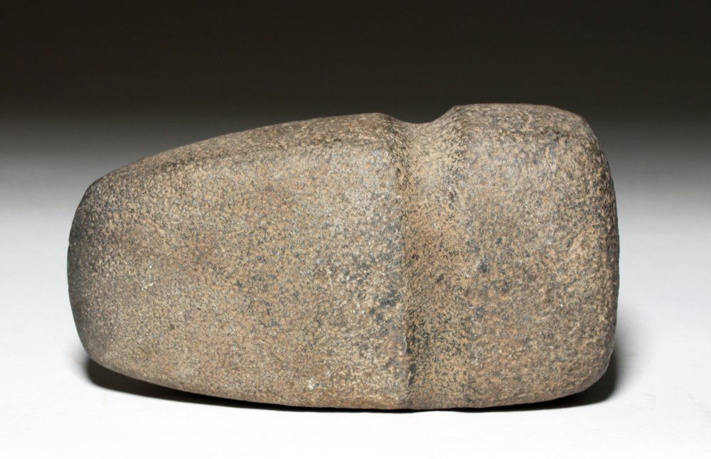 Large Stone Axe Head West Mexico Coast: Pre-Columbian, Mexico, ca. 0 BCE to 1500 CE. This is a Mexican basalt stone axe head with a carved groove for attaching it to a leveraging device. Size: 7-1/2" W x 4" H x 2-3/4" L (19 cm x 10 cm x 7 c