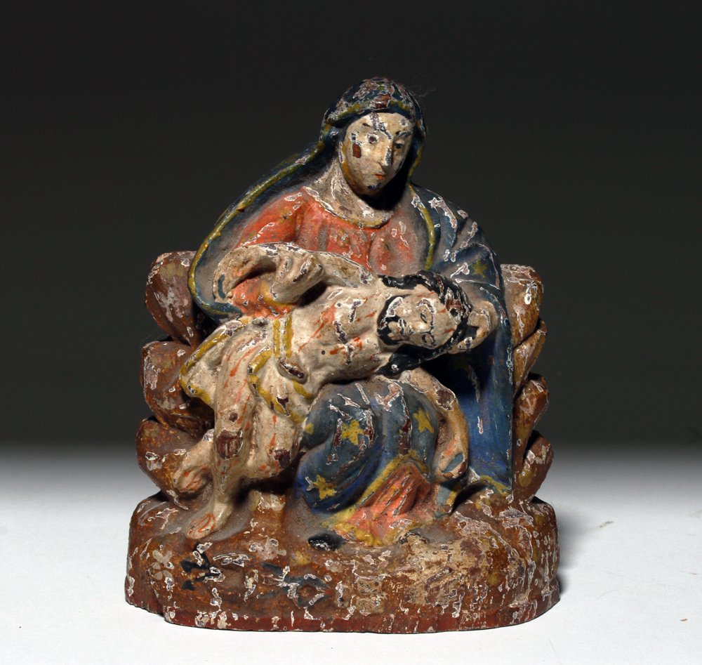 Antique Mexican Polychrome Wood Pieta: Latin America, Mexico, ca. early 20th century CE. A hand-carved wood sculpture depicting the Pieta, with the sorrowful Virgin Mary dressed in her traditional red gown and blue robe adorned with stars 