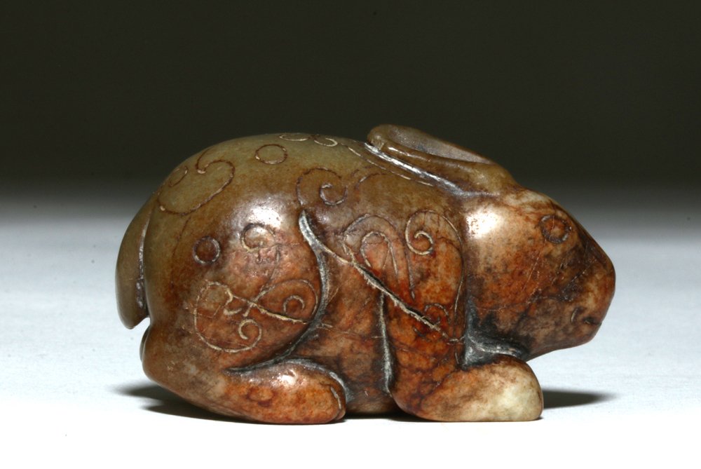 Chinese Qing Dynasty Carved Jade Rabbit: China, Qing (Ching) Dynasty, ca. 1644 to 1912 (but certainly made much earlier than 1912). Carved mutton fat jade rabbit standing on all fours, body incised with floral pattern, hole through body for