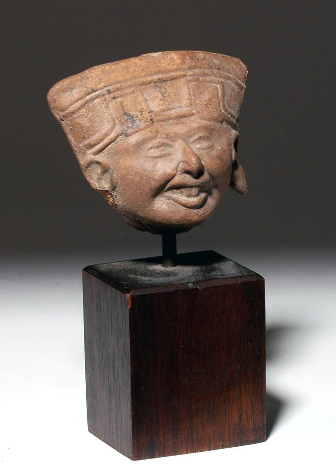 Veracruz Sonriente Pottery Head Whistle: Pre-Columbian, Gulf Coast Mexico, Vera Cruz, ca. 550 to 950 CE. A terracotta head of a Sonriente (smiling face)figural whistle, the most well-known of Remojadas figurines, featuring a traditional wide