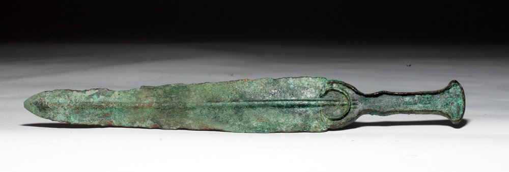 Luristan Bronze Flanged Dagger w/ Crescent Guard: Northern Iran, Luristan, ca. 1500 to 1000 BCE. This is a cast heavy bronze dagger with a thick rib and a decorative arch at the top of the blade. The hilt would have had an inlay at one time. Bronze A