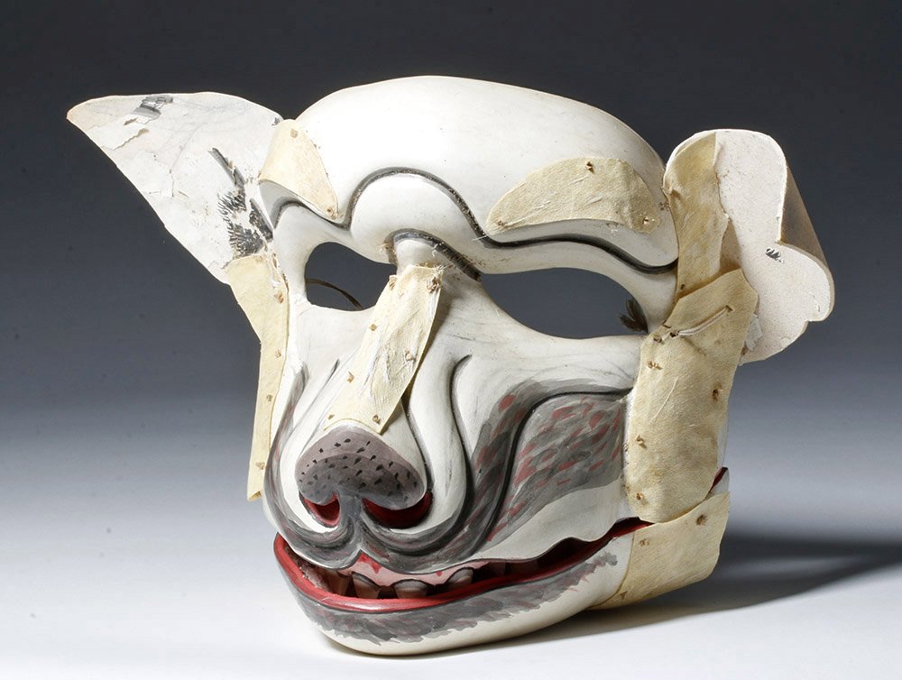Museum-Exhibited Indonesian Dog Face Mask from Bali: Indonesia, Bali, 20th century CE. This is a fantastic mask of a dog's head with accentuated snout, ears, and mouth, including pointed teeth. The ears are made of applied hide and there is inlaid fur o