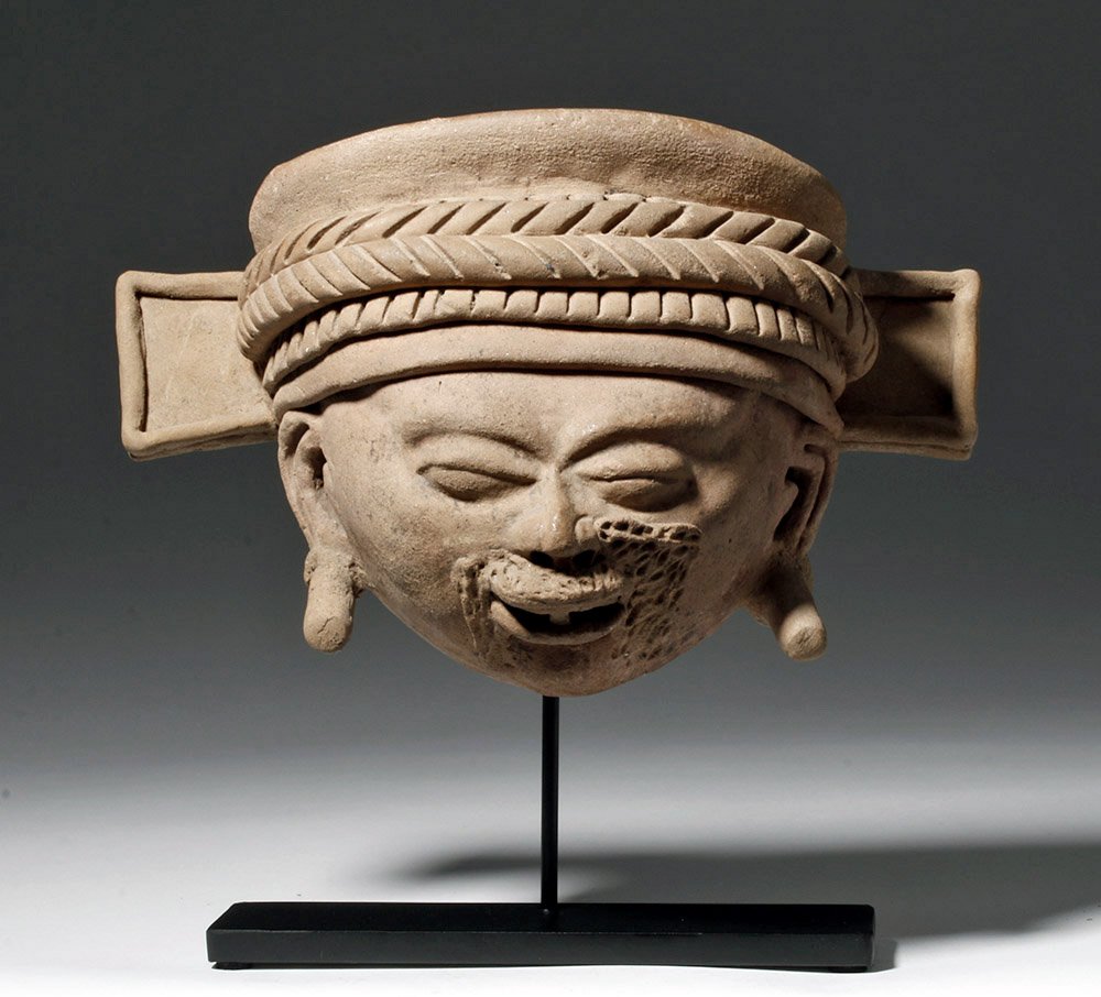Vera Cruz Terractotta Head of a Shaman: Pre-Columbian, Gulf Coast of Mexico, Remojadas,Veracruz, ca. 600 to 800 CE. A terracotta effigy head from a full figure of a fierce warrior with a lively countenance, impressively long ear flares, and