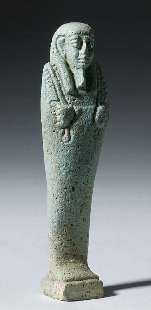 Egyptian Faience Ushabti - Late Period to Ptolemaic: Egypt, Late Period to Ptolemaic, 712 to 30 BCE. A faience ushabti, turquoise blue in color and depicted in mummiform, with his fisted hands holding agricultural implements, a seed bag over his left sh