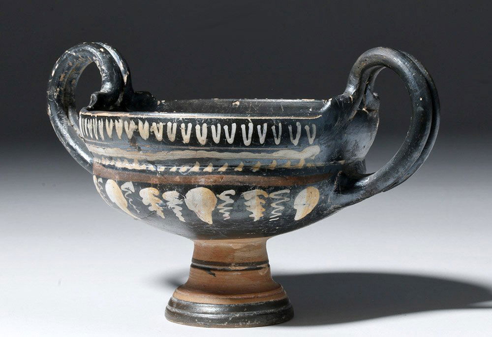 Greek Gnathian Pottery Kylix w/ Grapevines: Magna Graecia, Southern Italy, Campania, Gnathian, ca. 340 to 320 BCE. A wheel thrown, twin bifurcated handled kylix (drinking cup) with a corsetted body, raised on a stem from a round foot. The body