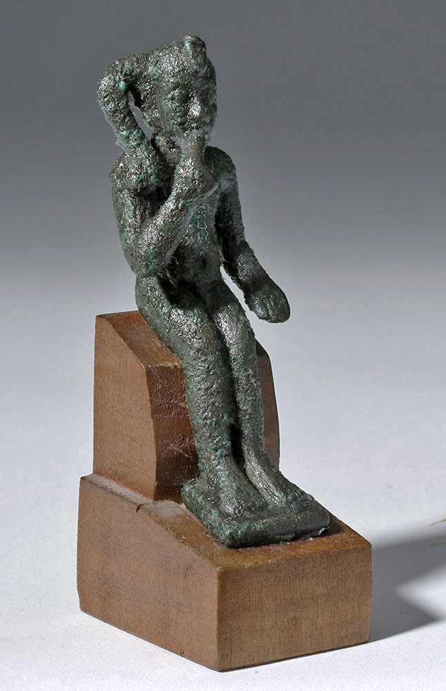 Egyptian Bronze Seated Statuette - Harpocrates / Horus: Egypt, Late Dynastic Period, Dynasties 26 through 30, ca. 662 to 330 BCE. A seated bronze figure of the child god Harpocrates, sitting nude, legs together with feet on an integral square base, right f