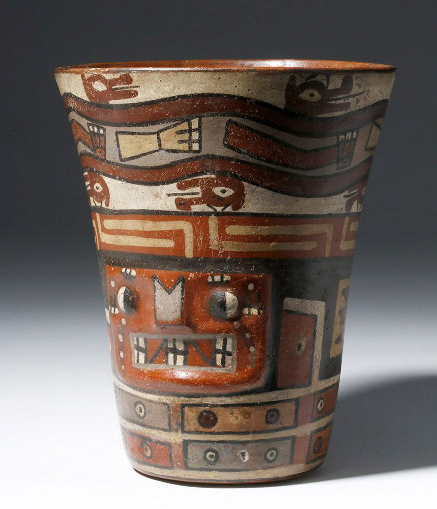 Important Wari Polychrome Pottery Human Figural Kero: Pre-Columbian, Peru, Huari/Wari, ca. 500 to 1000 CE. An stunning polychrome pottery kero featuring the expressive face of a shaman in transition or deity modeled upon the exterior wall with eyes, nose