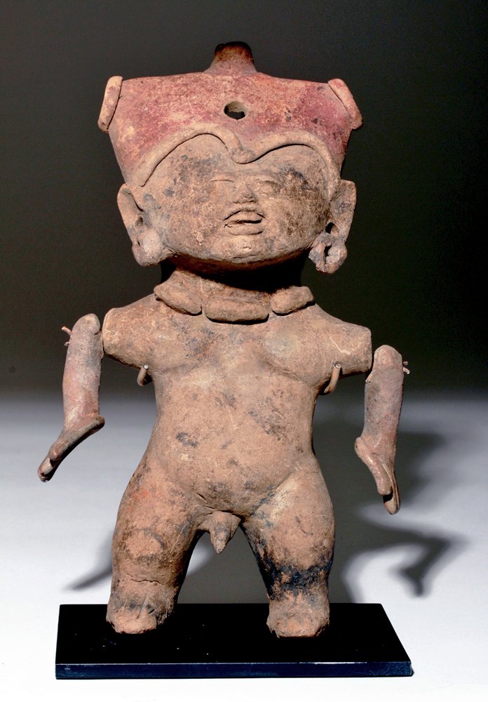 Articulated Vera Cruz Sonriente Whistling Figure: Pre-Columbian, Gulf Coast Mexico, Veracruz, ca. 600 - 900 CE. Hollow-molded buff terracotta standing male figure having separately made, articulated arms. The molded facial detail shows a small face w
