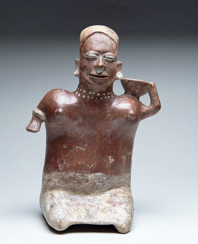 Jalisco Kneeling Female Bowl On Shoulder, ex-Messick: Pre-Columbian, West Mexico, Jalisco, ca. 500 BCE to 500 CE. Pottery seated female figure holding a bowl on her left shoulder, wearing small ear ornaments and nose ring. White painted beaded necklace a