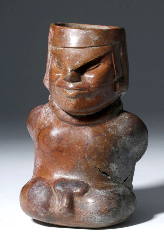 Moche Redware Effigy Vessel of Prisoner, ex-Museum: Pre-Columbian, North Coast Peru, Moche III to IV, ca. 200 to 500 CE. A redware jar in the form of a captured, bound, and very angry prisoner with his head modeled on the spout. He wears a helmet but i