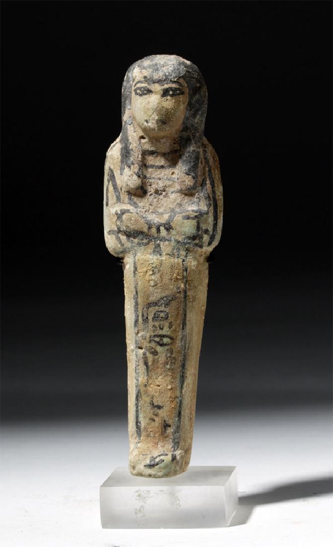 Egyptian Late Period Faience Ushabti: Egypt, Third Intermediate Period, ca. 1070 to 712 BCE. This is a late period ushabti (shabti), in mummiform with the arms holding hoes. It is made of pottery and painted with green faience and black d