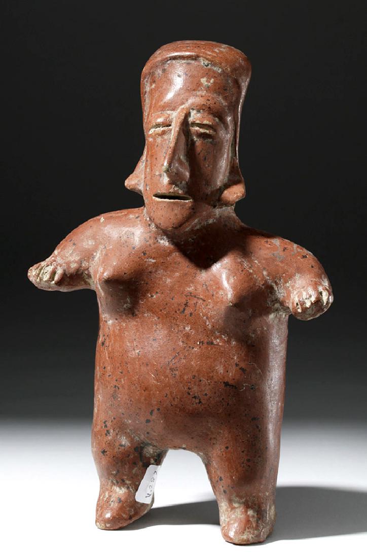 Fine Jalisco Pottery Standing Female Figure: Pre-Columbian, West Mexico, Jalisco, ca. 300 BCE to 300 CE. A fine redware figure of a woman with classical Jalisco features. She stands with her short legs and arms wide apart, with a large face and