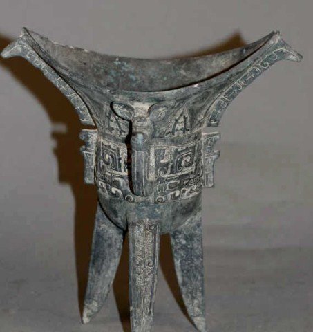 Carved Bronze Wine Cup: bronze wine cup, china, probably the Zhou DynastyCwith carved monster pattern on body, has been repaired. Condition small chip on one of the feet